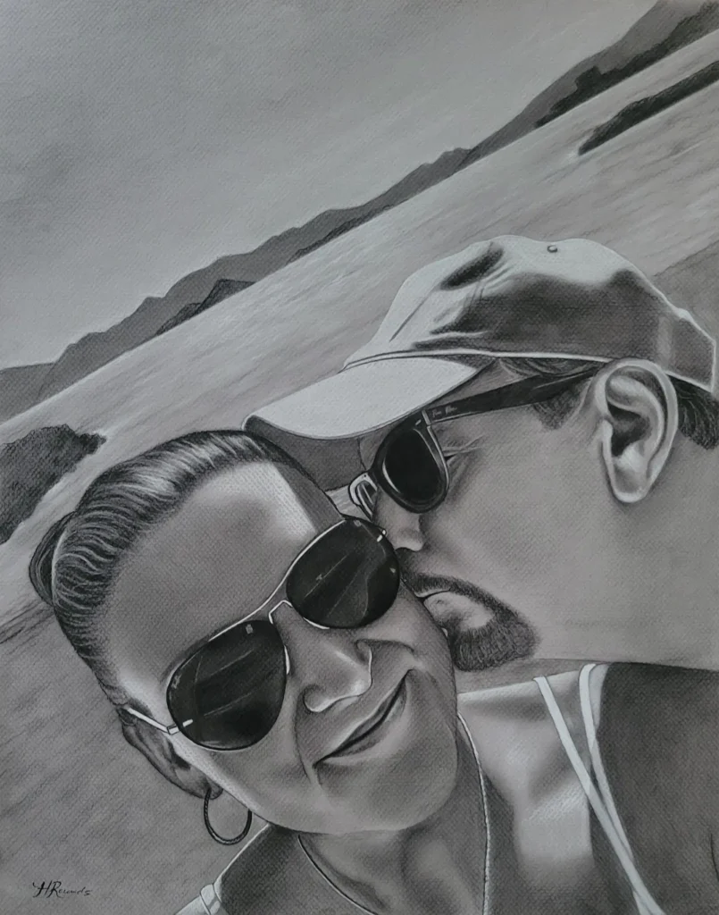 Commissioned Portrait Drawing of a Couple on the Beach, charcoal/pastel on toned paper, drawing of a man kissing a woman's cheek while sitting on the beach by Heidi Rounds.