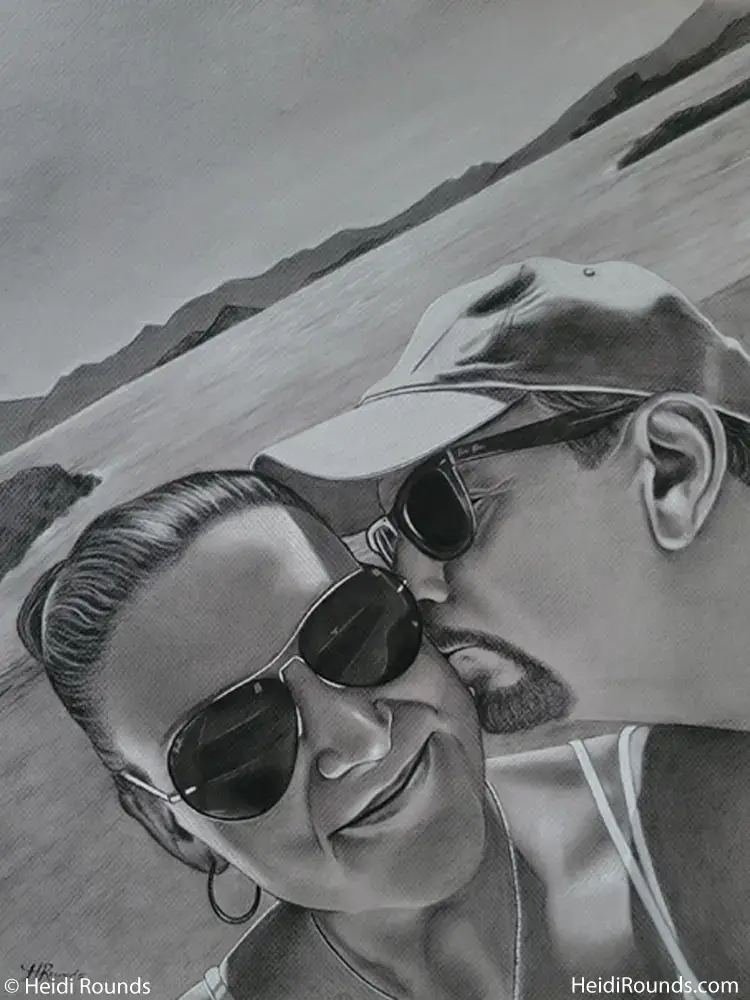"Commissioned Portrait Drawing of a Couple on the Beach" 16"x20" charcoal/pastel portrait drawing on toned paper by Heidi Rounds. A man kissing a woman on the cheek, both in sunglasses on the beach.